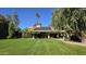 Expansive backyard featuring lush lawn, mature trees, solar panels, and covered patio space at 8637 E Appaloosa Trl, Scottsdale, AZ 85258