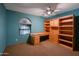 Bedroom with a built-in desk and shelves, a ceiling fan, and an arched window at 8637 E Appaloosa Trl, Scottsdale, AZ 85258