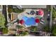 An aerial view of the backyard pool with red umbrellas and furniture, surrounded by lush landscaping and greenery at 9826 W Tonto Ln, Peoria, AZ 85382