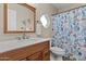 Well-lit bathroom features wood vanity with white countertop, decorative mirror, and a tiled shower with a stylish curtain at 9826 W Tonto Ln, Peoria, AZ 85382