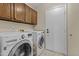 Functional laundry room equipped with a washer, dryer, and ample overhead storage cabinets for convenience at 9826 W Tonto Ln, Peoria, AZ 85382