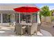 Outdoor patio showcases a dining table set with chairs under a red umbrella, perfect for alfresco dining at 9826 W Tonto Ln, Peoria, AZ 85382