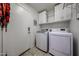 Functional laundry room equipped with modern washer and dryer units and storage shelves at 10832 W Piute Ave, Peoria, AZ 85373