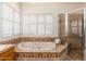 Bathroom showcasing a soaking tub and tiled shower area with bright, shuttered windows at 10901 E Quarry E Trl, Scottsdale, AZ 85262