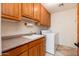 Cozy laundry room with wood cabinets, a sink, countertop, and a washing machine at 10901 E Quarry E Trl, Scottsdale, AZ 85262
