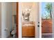A powder room with a wood vanity, tile countertop, toilet and an outside view at 10901 E Quarry E Trl, Scottsdale, AZ 85262