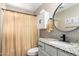 Clean bathroom with a granite vanity, oval mirror, storage, and a patterned shower curtain at 11133 E Dragoon Ave, Mesa, AZ 85208