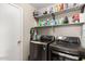 Laundry room featuring modern washer and dryer units with storage shelves above at 11133 E Dragoon Ave, Mesa, AZ 85208