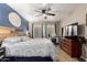 Main bedroom featuring blue accent wall, ceiling fan, wooden headboard, desk, and tiled floor at 11133 E Dragoon Ave, Mesa, AZ 85208