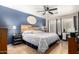 Main bedroom featuring blue accent wall, ceiling fan, wooden headboard, and a tiled floor at 11133 E Dragoon Ave, Mesa, AZ 85208