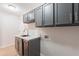 View of a kitchenette with gray cabinets, marble countertops, and stainless steel dishwasher at 13305 W Colter St, Litchfield Park, AZ 85340