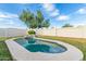A private pool in the backyard with a unique rock feature surrounded by lush grass at 13629 N 71St Dr, Peoria, AZ 85381