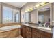Bright bathroom featuring double sinks, travertine floors, shutters, and a soaking tub with nice views at 15620 E Palomino Blvd, Fountain Hills, AZ 85268