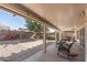 Large covered patio with wicker seating overlooking a gravel yard with mature trees and block wall fencing at 16232 W Montoya Dr, Surprise, AZ 85374
