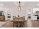A well-lit dining room shows an open floor plan, wood-look tile, and a rustic wood table with seating for six at 17431 W Via De Luna Dr, Surprise, AZ 85387