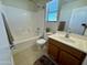 Bathroom featuring a toilet, a bathtub, a sink with wood cabinets, and a window at 17477 W Woodrow Ln, Surprise, AZ 85388