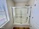 Bathroom with white tiled shower and tub combination behind sliding glass door at 17477 W Woodrow Ln, Surprise, AZ 85388