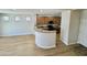 Open-concept living room and kitchen with breakfast bar, wood cabinets, and laminate flooring at 17477 W Woodrow Ln, Surprise, AZ 85388
