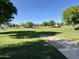 Neighborhood park with a vast expanse of green grass, trees, and walking paths at 17477 W Woodrow Ln, Surprise, AZ 85388