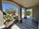 Arched porch with iron railing shows desert landscaping, a red car, and a tree at 17477 W Woodrow Ln, Surprise, AZ 85388