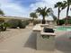 Outdoor kitchen and BBQ area with a sparkling pool and palm trees, perfect for entertaining at 19058 N Aztec Point Dr, Surprise, AZ 85387