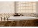 Luxurious bathroom features a soaking tub with mosaic tile and a glass block window at 22318 N Pico Ct, Sun City West, AZ 85375