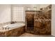 Luxurious bathroom with a soaking tub, walk-in shower with mosaic tile accents, and a glass block window at 22318 N Pico Ct, Sun City West, AZ 85375