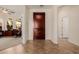 Elegant foyer with a dark wood door, neutral walls, and tile flooring, leading to a home office on the left at 22318 N Pico Ct, Sun City West, AZ 85375