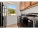 Bright laundry room equipped with modern appliances, storage cabinets, and natural light from a window at 22318 N Pico Ct, Sun City West, AZ 85375