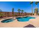 Refreshing pool and spa with rock landscaping, mature palm trees and decorative wall art under a clear blue sky at 22318 N Pico Ct, Sun City West, AZ 85375