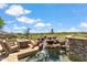 Resort-style pool area with a rock waterfall feature, a golf course view, and outdoor seating at 25150 N Windy Walk Dr # 37, Scottsdale, AZ 85255