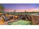 Backyard pool and spa with stone waterfall feature, desert landscaping, fire pit, and golf course views at 25150 N Windy Walk Dr # 37, Scottsdale, AZ 85255