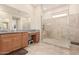 Bathroom featuring wood cabinets, granite countertops, and a tiled walk-in shower at 28623 N 66Th Ave, Phoenix, AZ 85083