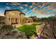 Backyard with putting green, gravel landscaping, and covered patio of a two-story home at sunset at 3601 N Sonoran Hts, Mesa, AZ 85207