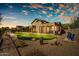 Backyard with putting green, gravel landscaping, and desert vegetation surrounding a two-story home at sunset at 3601 N Sonoran Hts, Mesa, AZ 85207