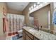 Neutral bathroom featuring a granite countertop, decorative mirror, and a shower-tub combination with colorful curtain at 3601 N Sonoran Hts, Mesa, AZ 85207