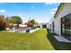 Backyard view of a modern swimming pool, lush green lawn, and desert landscaping at 3710 E Hazelwood St, Phoenix, AZ 85018