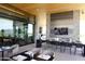 Outdoor dining area with modern seating, stone accents, wood ceiling, and scenic mountain views, offering a luxurious experience at 40215 N 110Th Pl, Scottsdale, AZ 85262