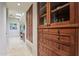 Detailed view of the hallway with a built-in wooden cabinet with glass doors and a bathroom in the background at 40215 N 110Th Pl, Scottsdale, AZ 85262