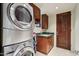 Well-lit laundry room featuring a stacked washer and dryer unit and wood cabinetry above a green countertop sink at 40215 N 110Th Pl, Scottsdale, AZ 85262