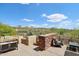 Outdoor patio area with comfortable seating, a stone privacy wall, and scenic desert views under a clear blue sky at 40215 N 110Th Pl, Scottsdale, AZ 85262