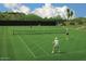 A well-maintained tennis court on a sunny day, surrounded by lush landscaping and blue skies at 40215 N 110Th Pl, Scottsdale, AZ 85262