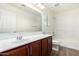 Bright bathroom features a large mirror over a vanity with dark wood cabinets and shower-tub combination at 4149 E Devon Dr, Gilbert, AZ 85296
