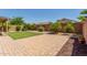 Private backyard features a brick paver patio, lush green turf, and mature landscaping at 42505 W Venture Rd, Maricopa, AZ 85138