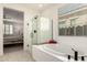 Modern bathroom with glass shower, soaking tub, and a large window providing natural light at 5612 N 109Th Ave, Phoenix, AZ 85037