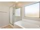 Bathroom featuring tub and shower combo with glass door, as well as a large window at 6319 W Hilton Ave, Phoenix, AZ 85043