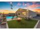 Inviting backyard oasis featuring a sparkling pool, cozy fire pit, and outdoor seating under festive string lights at 7145 E Eagle Nest Way, San Tan Valley, AZ 85143