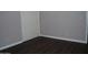 Minimal bedroom with dark wood-look floors, light grey walls, and a white closet door at 717 E State Ave, Phoenix, AZ 85020