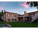 Exterior of a stone home with lush green lawn, a refreshing pool, and outdoor seating areas at sunset at 7525 N Shadow Mountain Rd, Paradise Valley, AZ 85253
