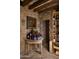 Stone wine cellar featuring a rustic wooden table with wine bottles and an adjacent wooden wine rack at 7525 N Shadow Mountain Rd, Paradise Valley, AZ 85253